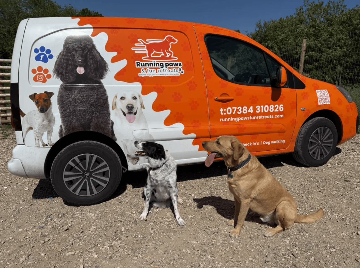A pair of dogs sat next to the Running Paws & Fun Retreats van